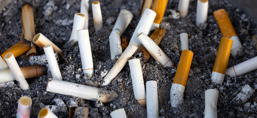 Cigarettes and ash on dirty sand in trash tray