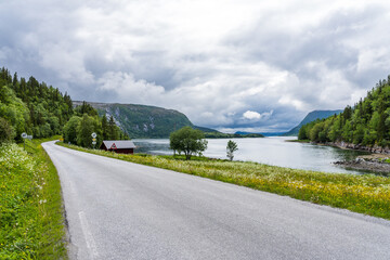 Fototapeta na wymiar Empty road next to a fjord in Norway with dark clouds in the sky