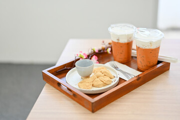 Iced Thai milk tea with snacks on a table. cafe or coffee shop dessert.