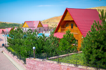 Cottage village with identical wooden houses. A beautiful street lined with trees. Roof covering of roofs with a tile.