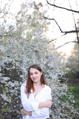 beautiful girl in a white shirt near a blooming tree. Beautiful warm spring and blossoming trees