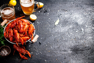 Boiled crayfish in a colander and a glass of beer. 
