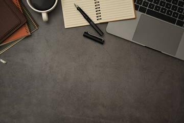 Laptop computer, blank notepad, coffee cup and pen on dark stone background. Flat lay, Top view...