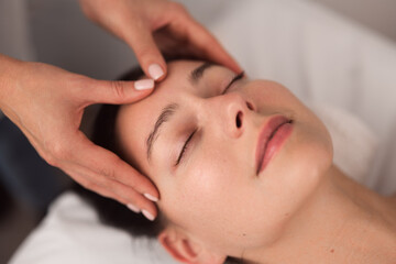 Fototapeta na wymiar Anonymous masseuse doing face massage to relaxed female customer