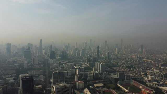 Bangkok, Thailand - January 24, 2023: Aerial drone view of a thick layer of air pollution and dust covering the city during morning time.