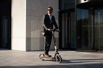 Young business man in a suit riding an electric scooter on a business meeting. Ecological...