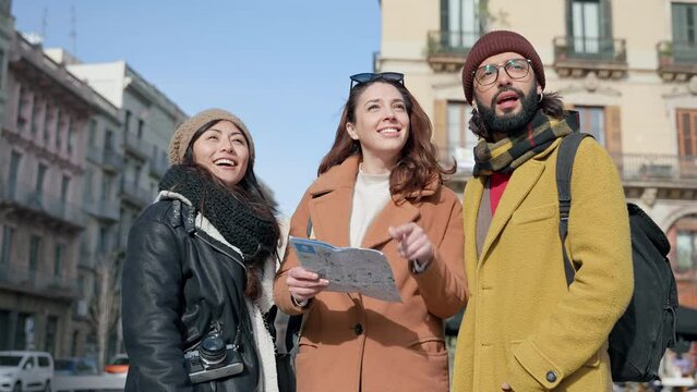 Friends checking city map searching for tourist destination in winter vacations 