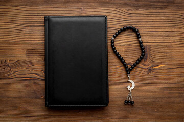 Koran book and black Muslim rosary with silver crescent moon