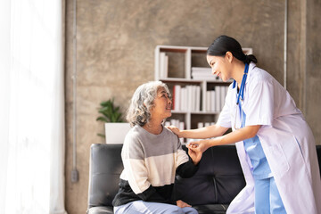 Obraz premium Young caregiver helping senior woman walking. Nurse assisting her old woman patient at nursing home. Senior woman with walking stick being helped by nurse at home.