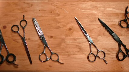 Male barber hand in rubber glove choosing scissors for haircut from wooden table top view closeup