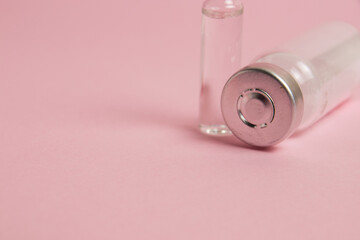 Ampoules with medicine or vitamins on pink paper background with copy space
