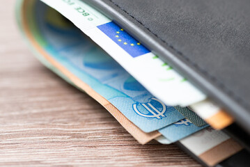 Macro shot of european money banknotes in the grey wallet. Focus on euro symbol and flag of the...