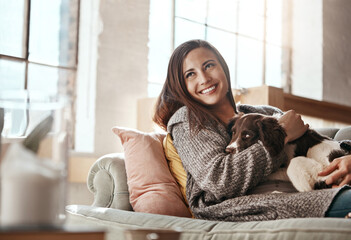 Woman relax on couch with dog, smile and content at home with pet and happy together with peace in...