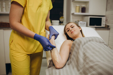 Obraz premium Waxing. Depilation hand and arm of the young woman lying in the spa salon