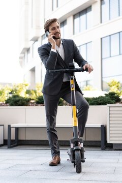 Elegant handsome businessman is riding an electric scooter and using his mobile phone