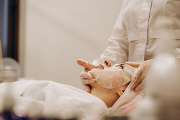 Cosmetologist applying mask on woman's face in spa salon, top view. Space for text