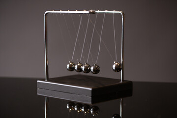 Closeup metal Newton cradle placed on gray background as representation of momentum concept