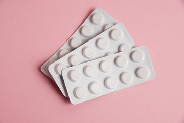 Pills in white blisters on a pink background with copy space, flat lay