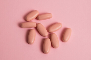 Obraz na płótnie Canvas Pink pills on pink paper background with copy space. Concept of taking vitamins in pill form