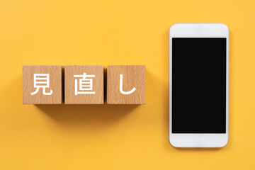 見直しと書かれたブロックとスマホ