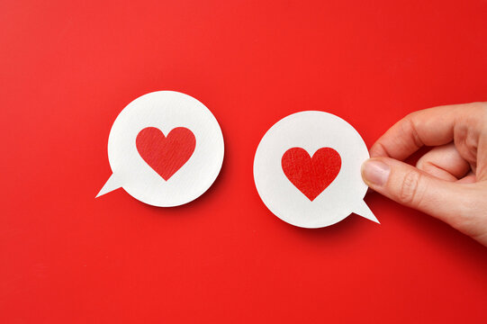 A red paper heart on conversational clouds. A symbol of love, conversation and declaration of love.