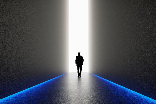 The silhouette of a man walking towards a bright light in the opened huge wall. A light in the end of a tunnel. The concept of success, freedom of choice, open mind, meditation.