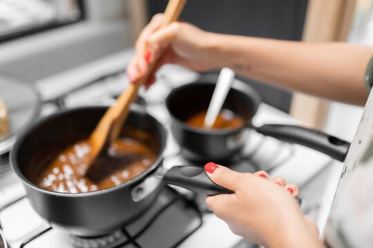 A young woman is preparing mole sauce using a gas stove with painted red nails