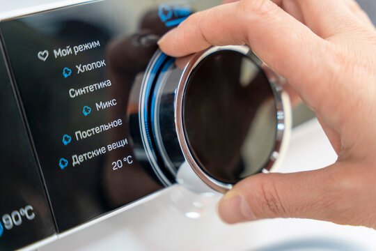 woman's hand selects the washing mode with a round selector