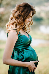 Pregnant woman touching her big belly and walking in the park relaxing in outside. Concept of pregnancy.