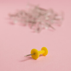 Yellow push pin macro on paper pink background with copy space