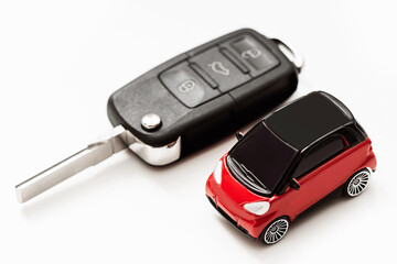 Toy red car with black roof next to a black car key