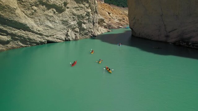 A group of kayaks floats on the river through the canyon. Spirit of adventure and competition. Epic nature view. 