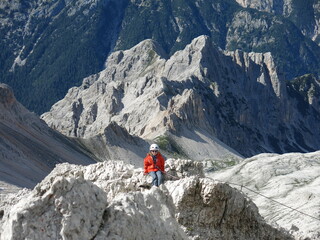 Fototapeta na wymiar Little girl going ferrates in Dolomite Alps in Italy. What a beautiful view among the mountains!