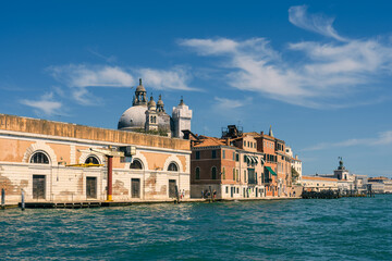 Fototapeta na wymiar Real old houses along the sea in the street of Venice along the Grand Canal on a sunny day, a seagull in the blue sky, a cargo crane at the edge of the sea, the main sea street of Venice, Italy travel