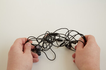 Tangled headphone wires in hands. tangled wire problem. Old used headphones and wires tangled...