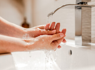 Girl washing hands with soap in bathroom