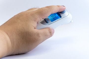 Human hand hold a digital infrared thermometer for body temperature scan from Coronavirus disease...
