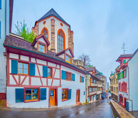 Medieval Rheinsprung street with historic half-timbered houses and huge apse of Martinskirche on the hill, Basel, Switzerland