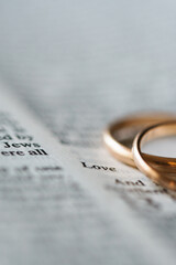 Two golden wedding rings and opened pages of holy bible represents the concept of marriage and the...