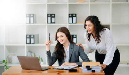 Two business workers talking on the smartphone and using laptop at the office.