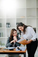 Businesswomen work and discuss their business plans. A Human employee explains and shows her colleague the results paper in modern office..