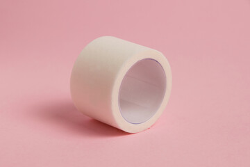 White medical patch on a paper base, for applying bandages, on a pink background