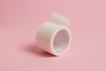 White medical patch on a paper base, for applying bandages, on a pink background