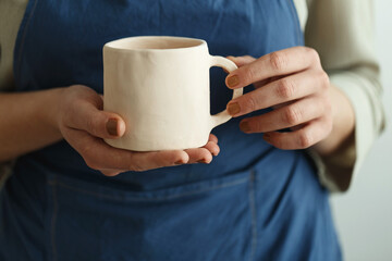 An artisan unrecognisable woman holds a handmade ceramic cup in her hands. Small business