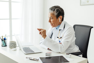 Telemedicine in action: Mature female doctor conducting a virtual consultation in her office