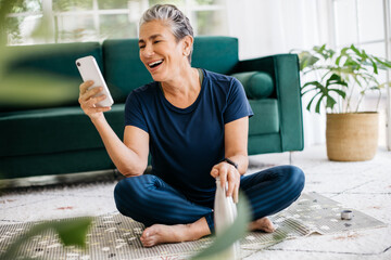 Happy with her fitness progress, mature woman looking at a workout app on her smartphone