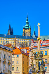 Spires of St. Vitus Cathedral and buildings on the hill through the Holy Trinity Column on Malostranske Namesti, Czechia
