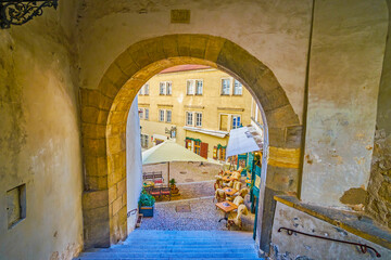 The view through the medieval arch on outdoor restaurant on Radnicke Schody staircases in Hradcany district of Prague, Czechia