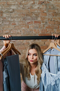 Young beautiful woman and clothing rack with different outfits