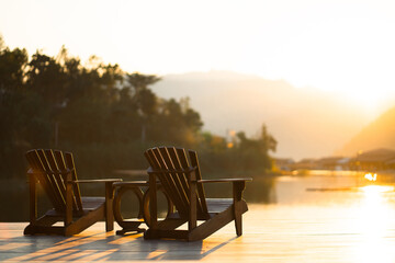 Fototapeta premium Classic wooden tables and chairs for relaxing by the resort's waterfront in the evening sun